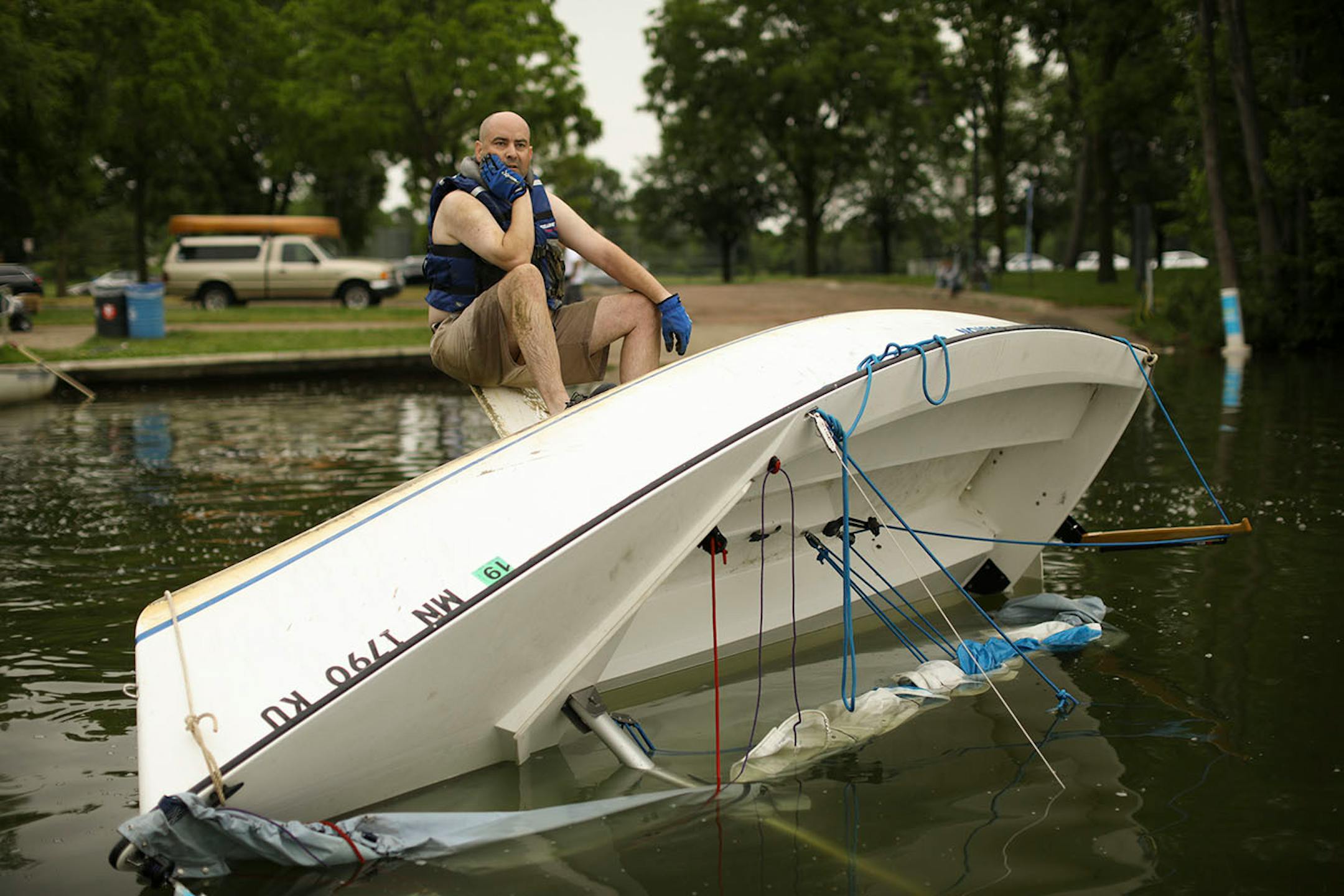 Martin Conroy waited for some help from others as he attempted to right his overturned sailboat on Lake Nokomis Sunday afternoon. When he drove past the lake after the storm Sunday morning, "I saw that I was the only one flipped, so I went home and changed for my unplanned afternoon adventure."