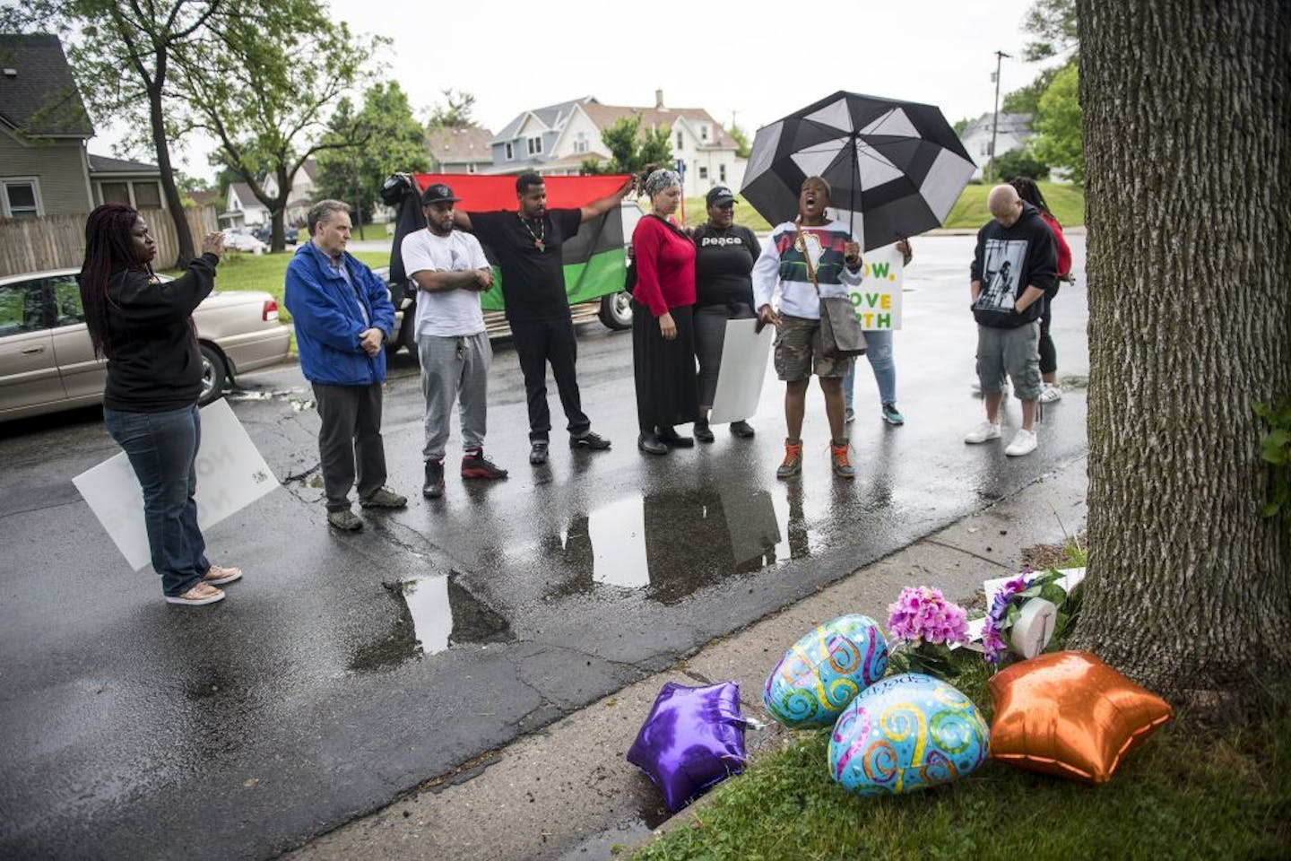 Pastor Carmen Means, carrying an umbrella, led community members in prayer at the site of a memorial for Birdell Beeks, the 59-year-old woman killed in a shooting Thursday night.