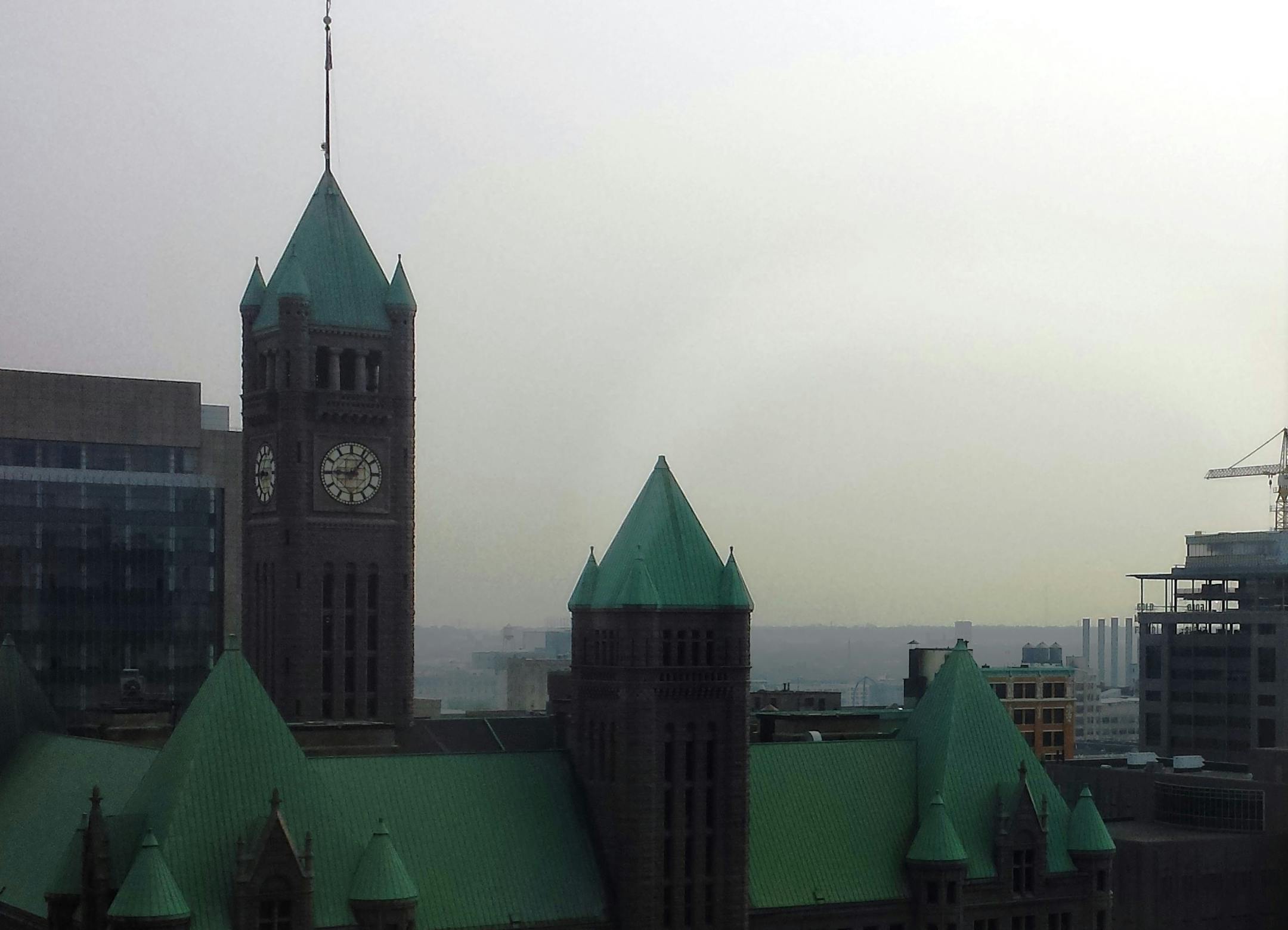 Looking past the rooftop of City Hall from downtown Minneapolis, a haze caused by Canadian wildfires hugs the trees and rooftops of the surrounding community.