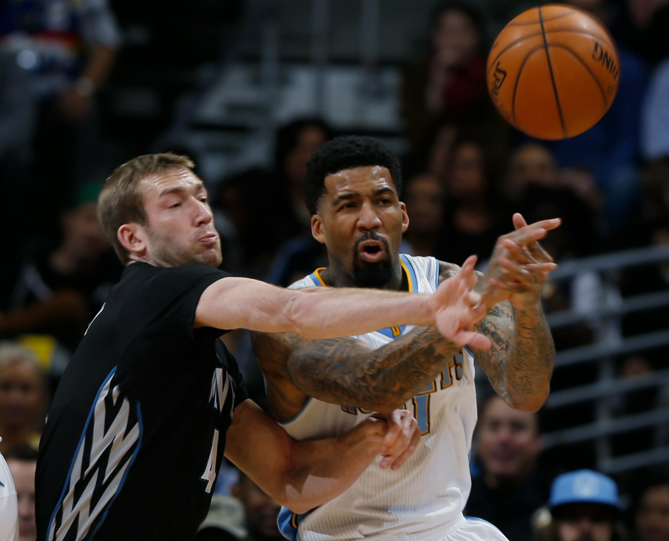 Minnesota Timberwolves forward Robbie Hummel, left, deflects pass for Denver Nuggets forward Wilson Chandler in the first quarter of an NBA basketball game Saturday, Jan. 17, 2015, in Denver. (AP Photo/David Zalubowski)