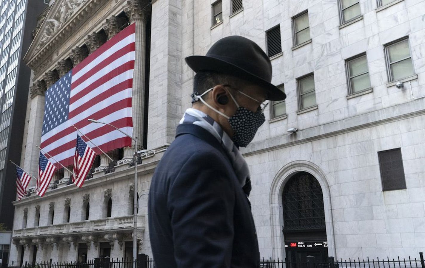 A man wearing a mask passes the New York Stock Exchange, Monday, Nov. 16, 2020, in New York. Stock markets are rallying on news that a second coronavirus vaccine shows promise.