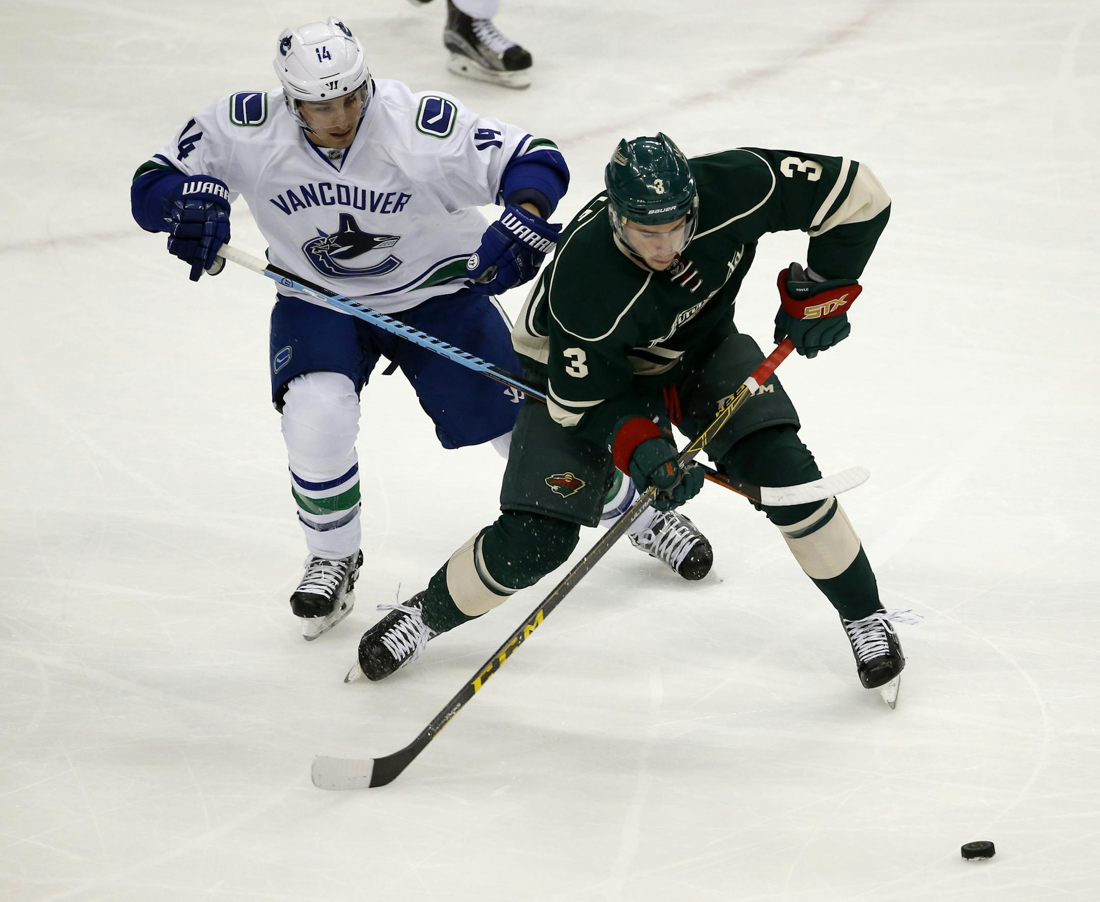 Minnesota Wild center Charlie Coyle (3) and Vancouver Canucks left wing Alex Burrows (14) chase the puck during the first period of an NHL hockey game in St. Paul, Minn., Wednesday, Nov. 25, 2015. (AP Photo/Ann Heisenfelt)
