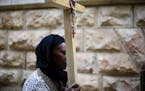 A Christian worshiper carries a cross walk along the Via Dolorosa towards the Church of the Holy Sepulchre, traditionally believed by many to be the s
