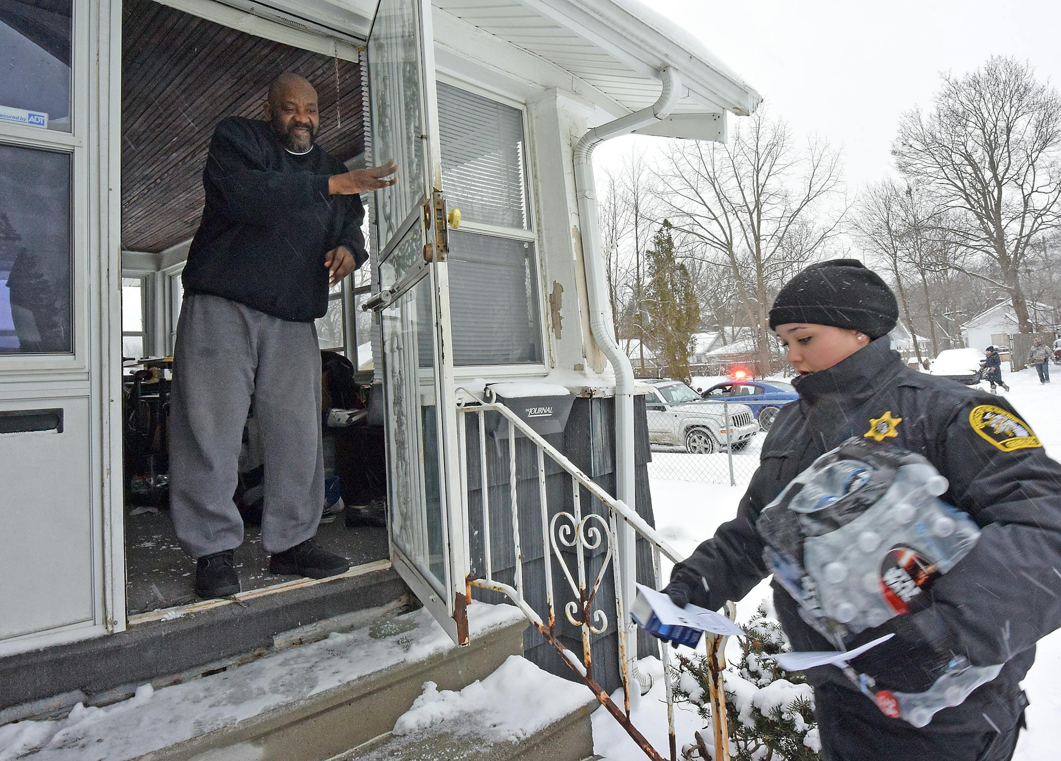 Samuel Smith is happy to receive a case of bottled water and a new water filter at his home on Mallery St. in Flint, Mich., as volunteers accompanied by Michigan State Police and Gennessee County Sheriff's Deputies bring residents water filters and bottled water on Tuesday Jan 12, 2016. Volunteers and police carrying bottled water, filters and lead test kits knocked on doors in Flint on Tuesday, seeking to help residents in the Michigan city that's confronting a water crisis. (Dale G. Young/The