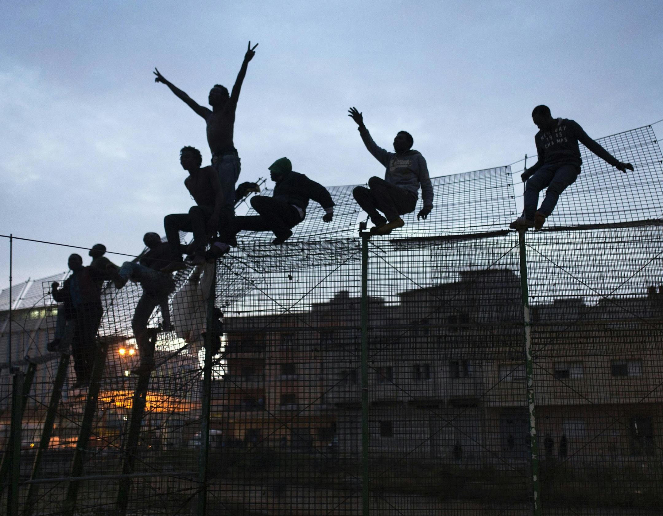 FILE - In this Friday, March 28, 2014, file photo, Sub-Saharan migrants climb over a metallic fence that divides Morocco and the Spanish enclave of Melilla. Since the early 1990s, Spain has built six-meter (20-foot) layered border fences around its two North African enclaves, Ceuta and Melilla, to help dissuade migrants, now mostly from sub-Saharan countries, from entering the cities from Morocco in the hope of reaching a better a life in Europe. (AP Photo/Santi Palacios, File)