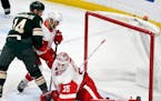 Detroit Red Wings goalie Jimmy Howard (35) has the puck roll off the end of his pad as the Red Wings' Nik Jensen, center, holds Minnesota Wild's Joel 