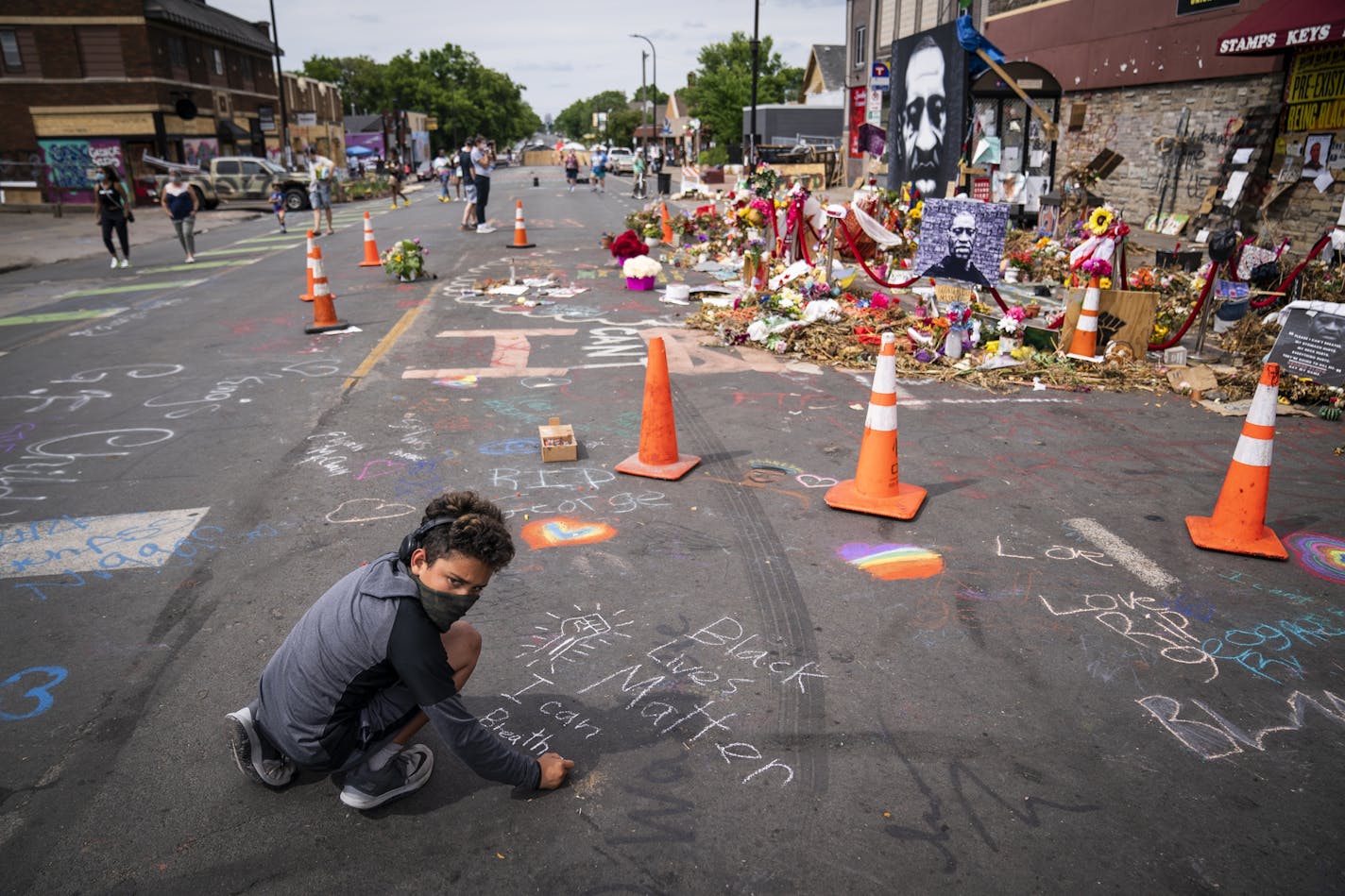 Anthony Land-Closson, 11, of Wheat Ridge, Colo., draws with chalk at the George Floyd memorial outside Cup Foods, Thursday, June 25, 2020, in Minneapolis.