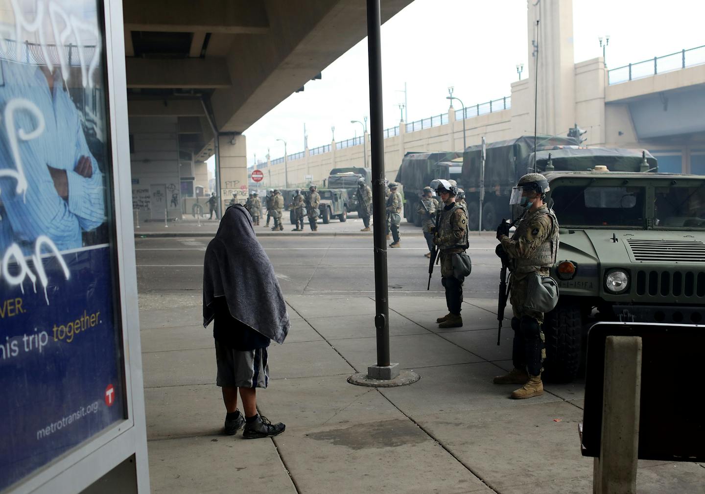 A man wrapped in a blanket talked to Minnesota National Guard members underneath the Hiawatha Bridge at Lake Street Friday morning in Minneapolis.