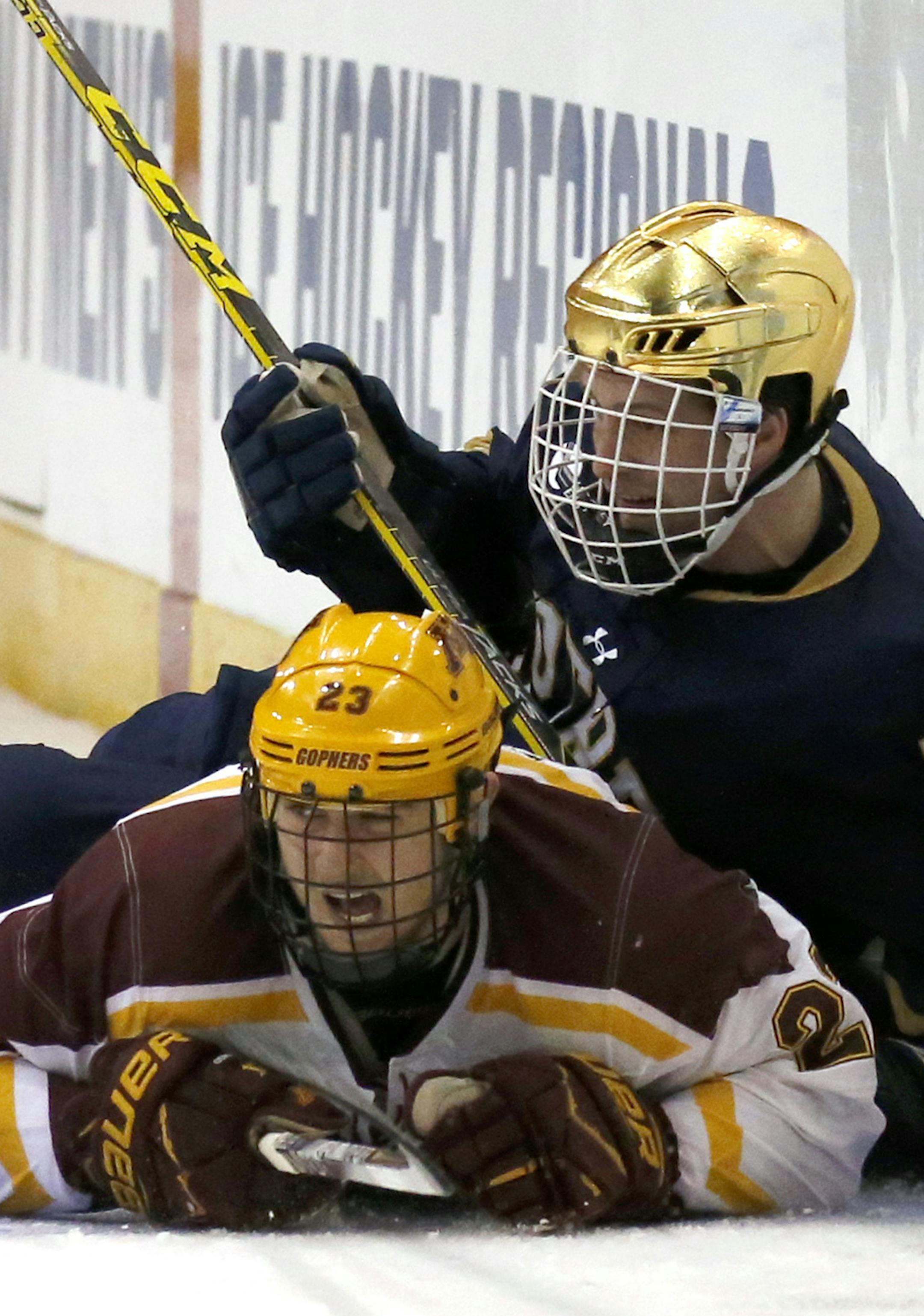 Minnesota's Ryan Norman (23) and Notre Dame's Ben Ostlie (8) crash into the boards during the second period of an NCAA regional men's college hockey tournament game, Saturday, March 25, 2017 in Manchester, N.H. (AP Photo/Mary Schwalm)
