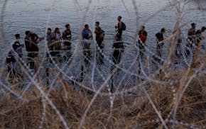 FILE - Migrants wait to climb over concertina wire after they crossed the Rio Grande and entered the U.S. from Mexico, Sept. 23, 2023, in Eagle Pass,