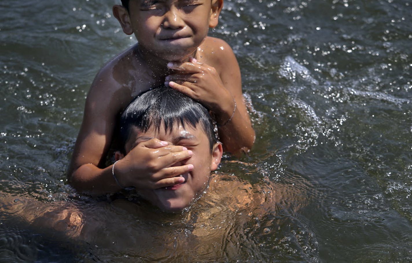 Seth Yang, 9, held onto Bruce Xiong, 13, while swimming Wednesday at Wirth Lake in Theodore Wirth Park in Minneapolis.