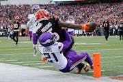 Bengals wide receiver Tee Higgins reaches the ball over the goal line against Vikings cornerback Akayleb Evans for a touchdown late in the fourth quar