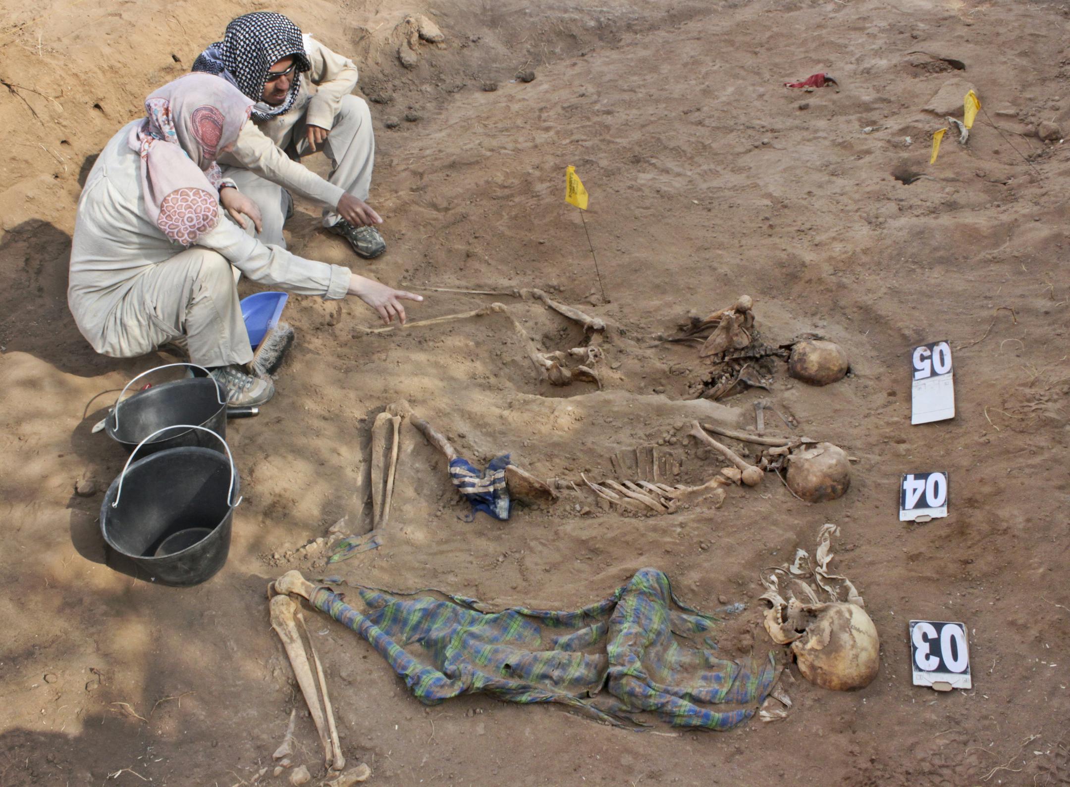 In this photo taken Tuesday, Feb. 18, 2014, members of the Peruvian Forensic Anthropology Team work to uncover bodies buried in a mass grave in Hargeisa, Somaliland, a breakaway region of Somalia. An American volunteer gently brushes away dirt to reveal the bones of a Somali victim buried in a mass grave some 30 years ago. Tens of thousands of skeletons may lie in mass graves here, on the northern edge of Somalia, where many want to see justice prevail, even if delayed. Last year 38 bodies were