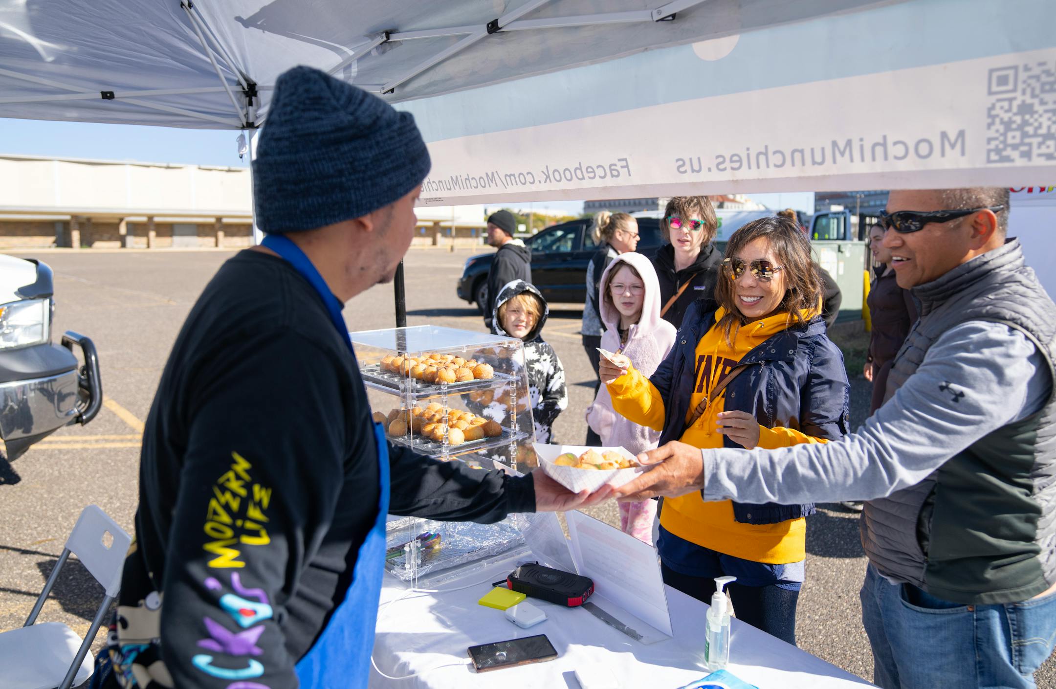 Bobby Yang sells mochi puffs to customers Sunday, Oct. 08, 2023, at a pop-up market in the parking lot of the old Sears Building in St. Paul, Minn. ]