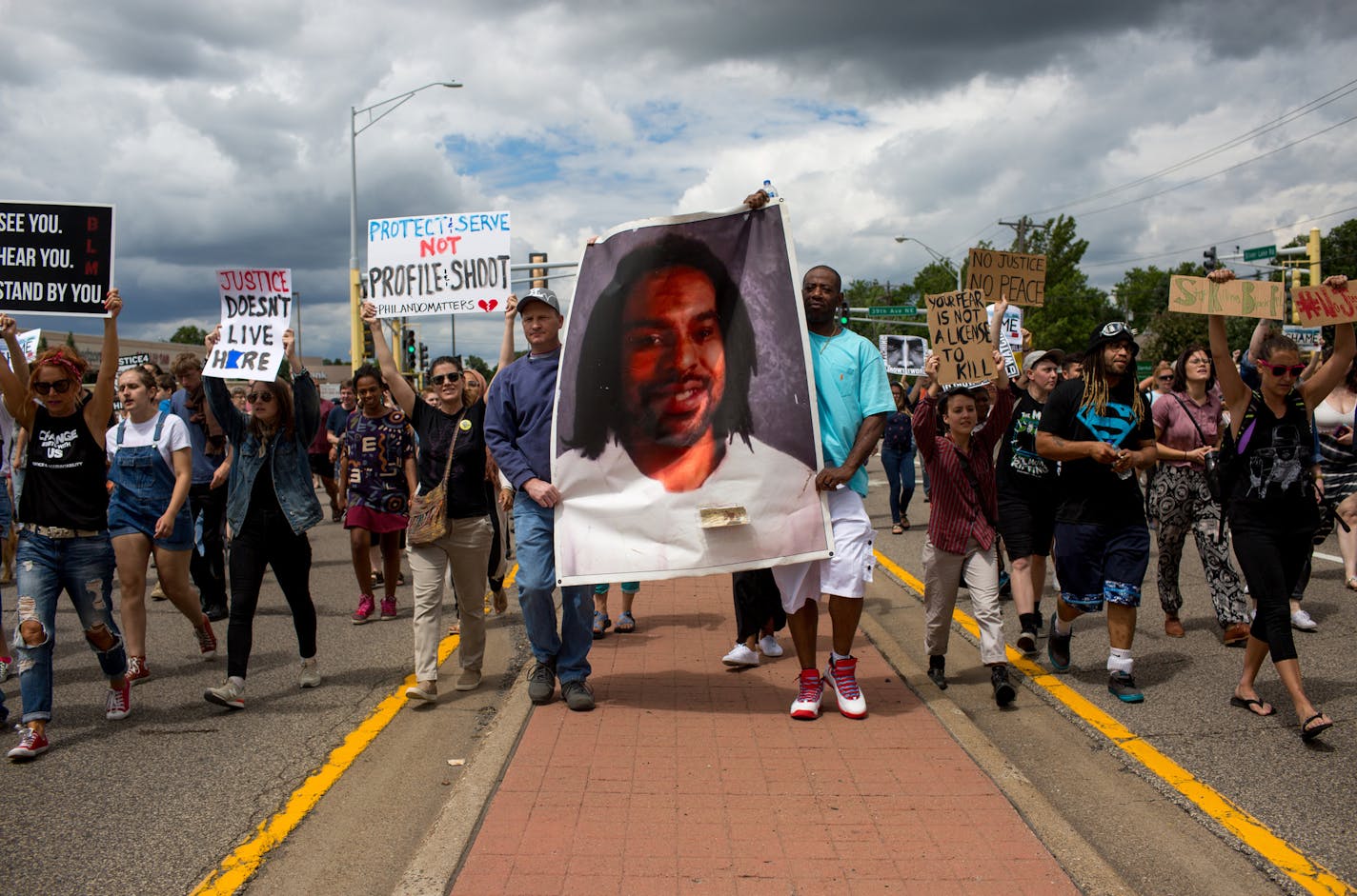 Protesters hold an image of Philando Castile and march down the street during a protest on Sunday, June 18, 2017 in St. Anthony, Minn. (Courtney Pedroza/Minneapolis Star Tribune/TNS) ORG XMIT: 1204347 ORG XMIT: MIN1706181804430627