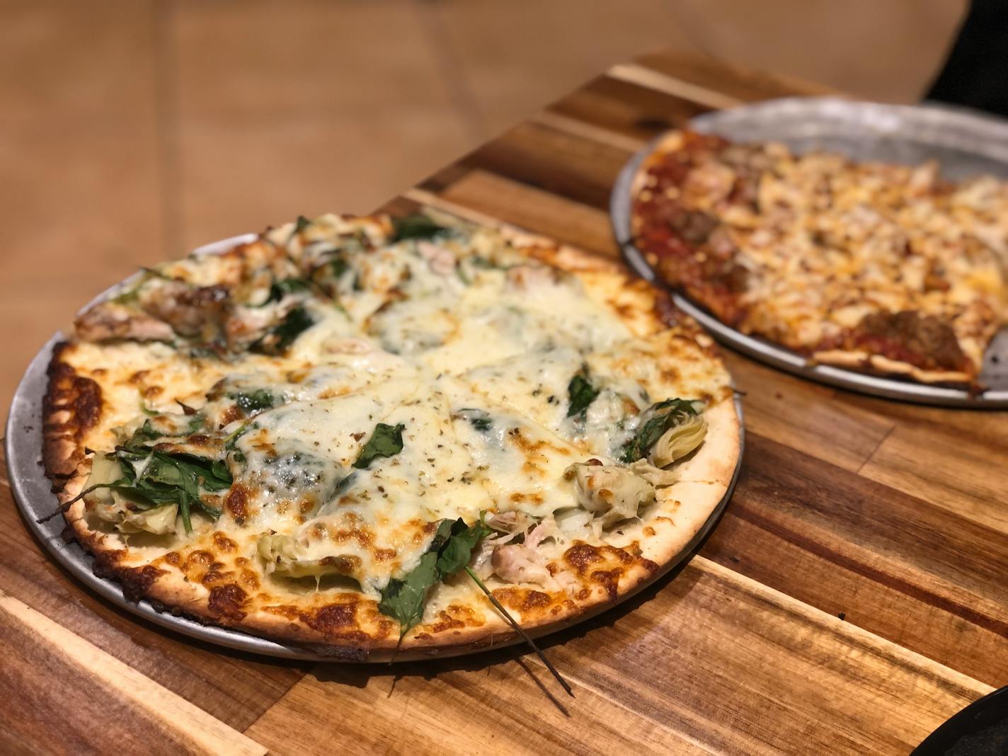 House-smoked chicken, artichokes and spinach are layered on a thin-crust pizza with white sauce at Scratch in Eagan.