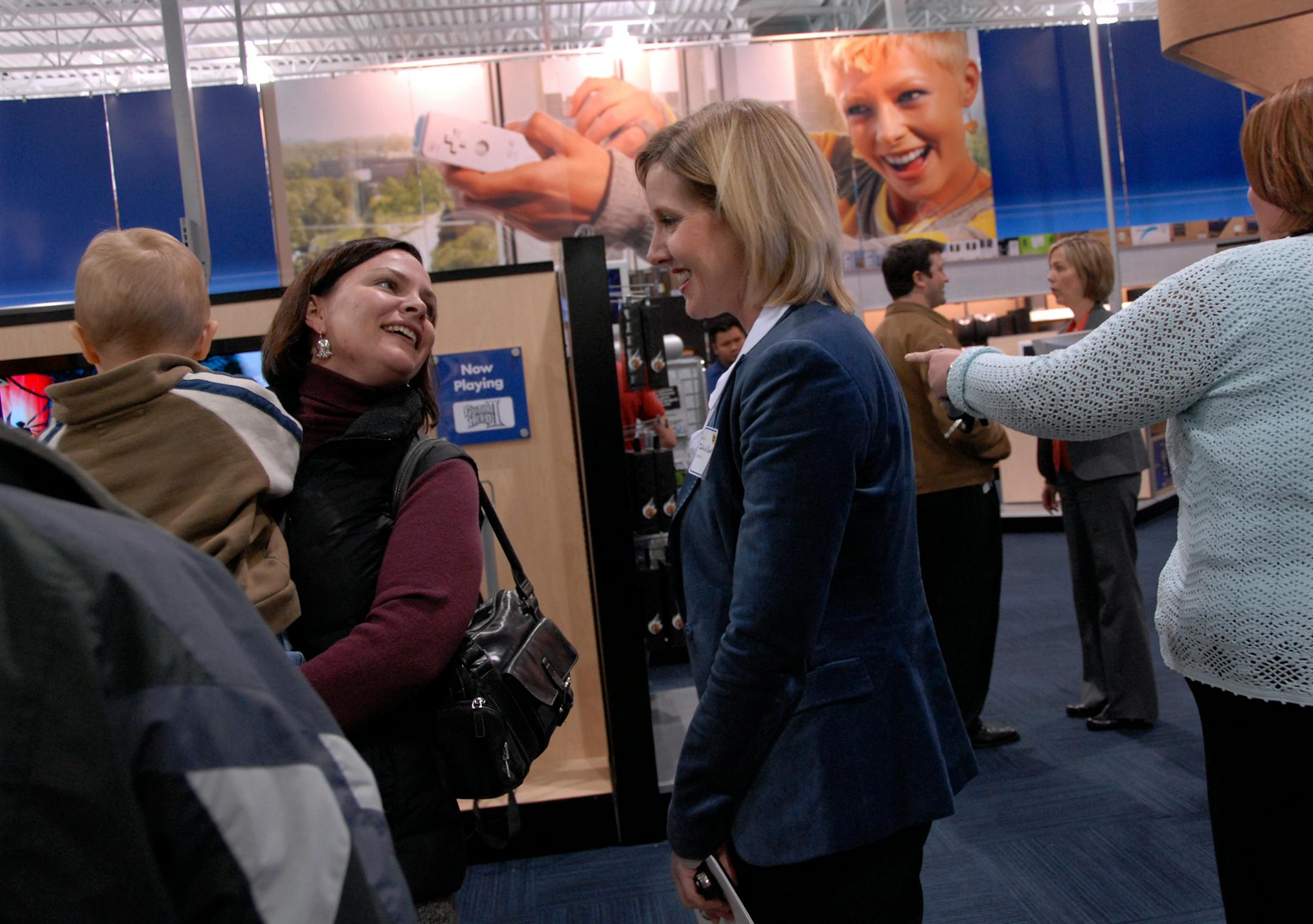 JOEY MCLEISTER � jmcleister@startribune.com Shakopee,Mn.,Weds.,Oct. 24, 2007--(At center) Best Buy Senior Vice President Julie Gilbert visited with colleagues and their family members during the pre-opening of the Best Buy Store in Shakopee. Gilbert has made an effort to reach out to women shoppers which is evident in the display photos on the walls.