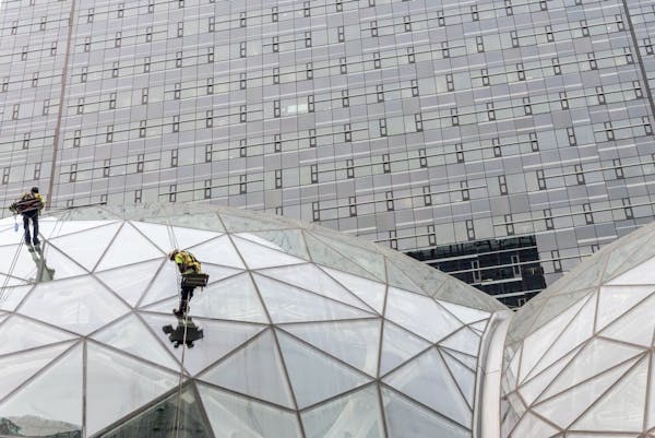Window washers work on a recently built trio of geodesic domes that are part of Amazon's headquarters building, visible in the background, in Seattle,