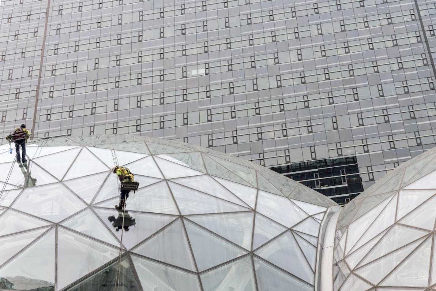 Window washers work on a recently built trio of geodesic domes that are part of Amazon's headquarters building, visible in the background, in Seattle, Sept. 7, 2017. The online retail giant said it was searching for a second headquarters in North America in 2017, a huge new development that would cost as much as $5 billion to build and run, and house as many as 50,000 employees.