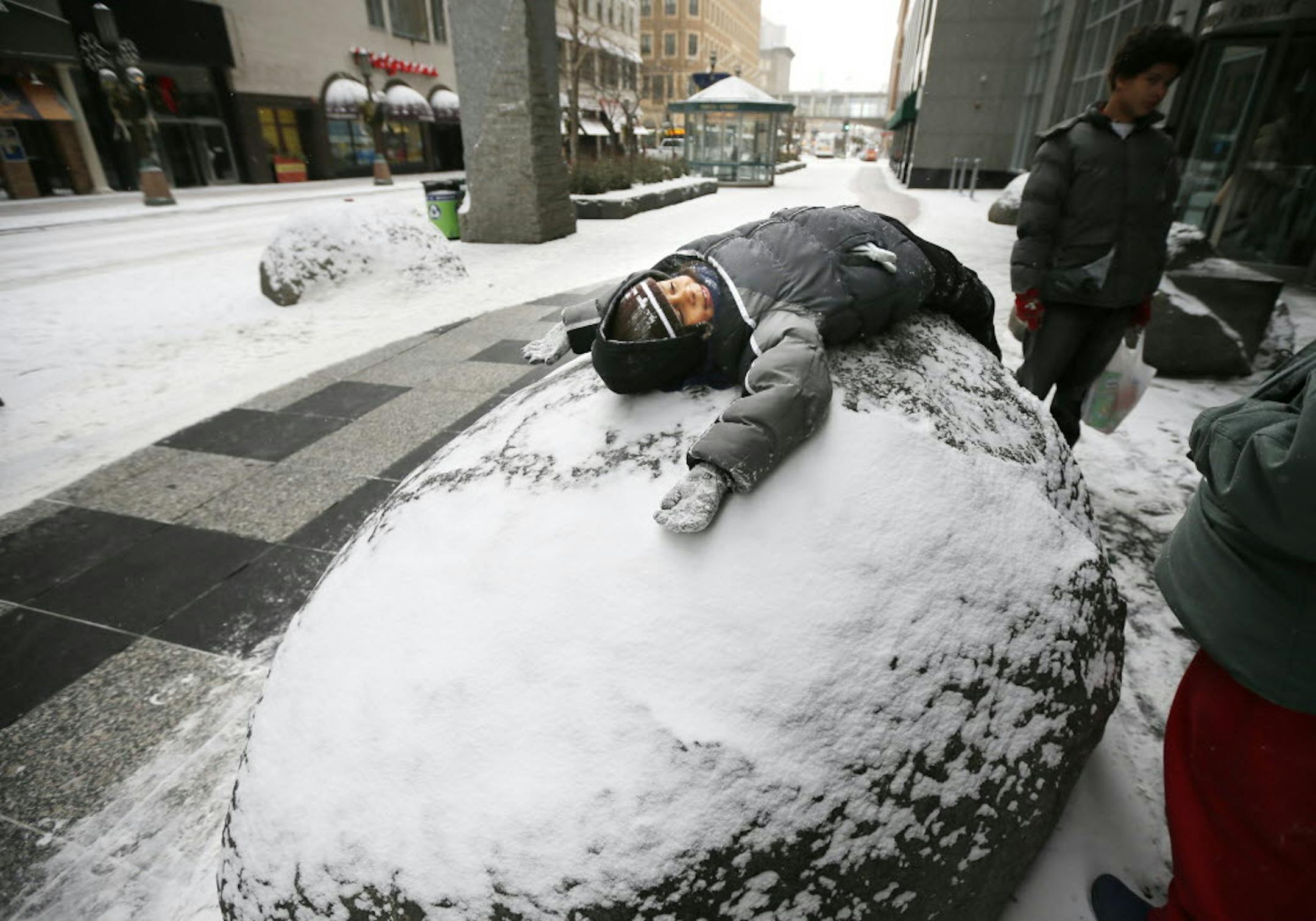 Tupac Hall 7, played in the snow as he waited for the bus with his parents along the Nicollet Mall Monday.