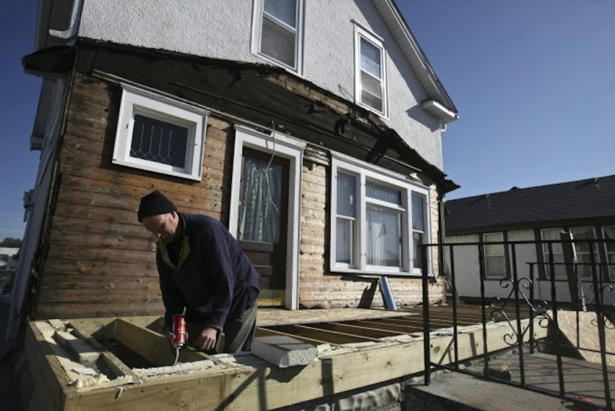 A man puts in insulation on the front porch of a home damaged by the tornado. Photo by Kyndell Harkness