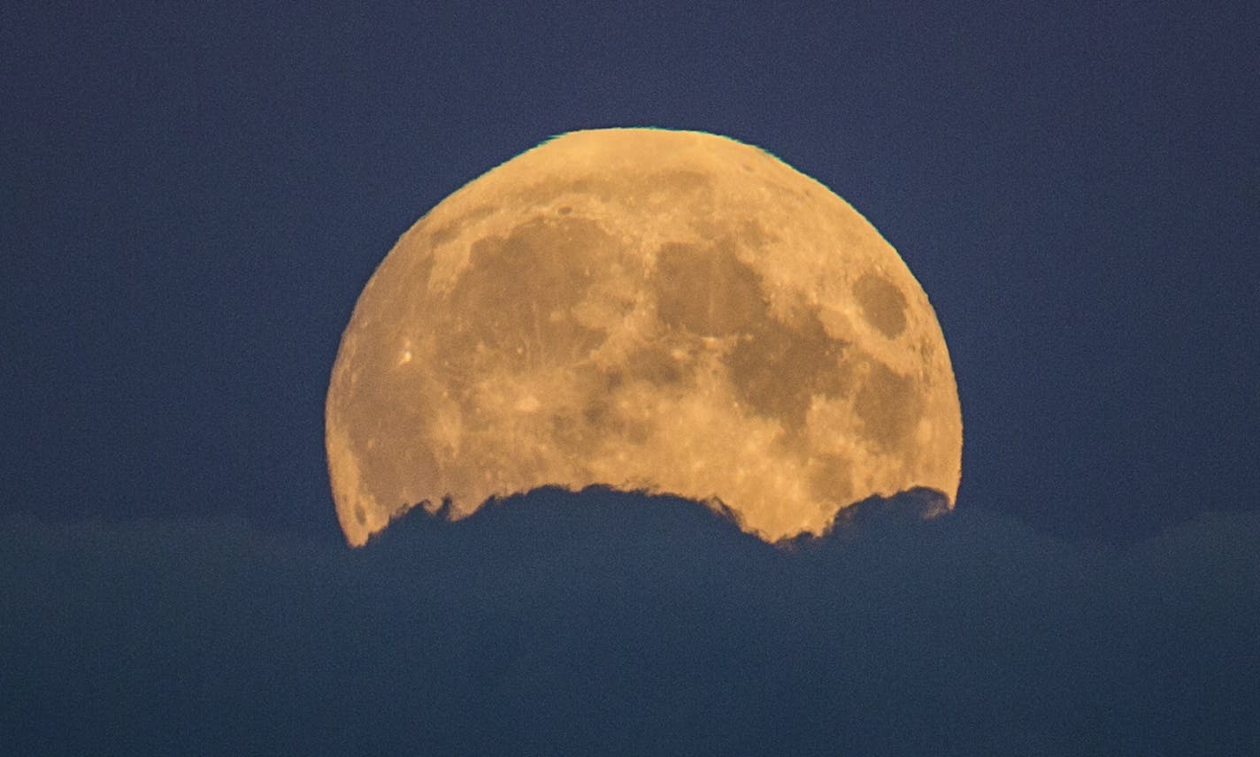 A full moon rises between clouds in Berlin, Germany, Sunday, Sept. 27, 2015. The full moon was seen prior to a phenomenon called a "Super Moon" eclipse that will occur during moonset on Monday morning, Sept. 28. (AP Photo/Gero Breloer)