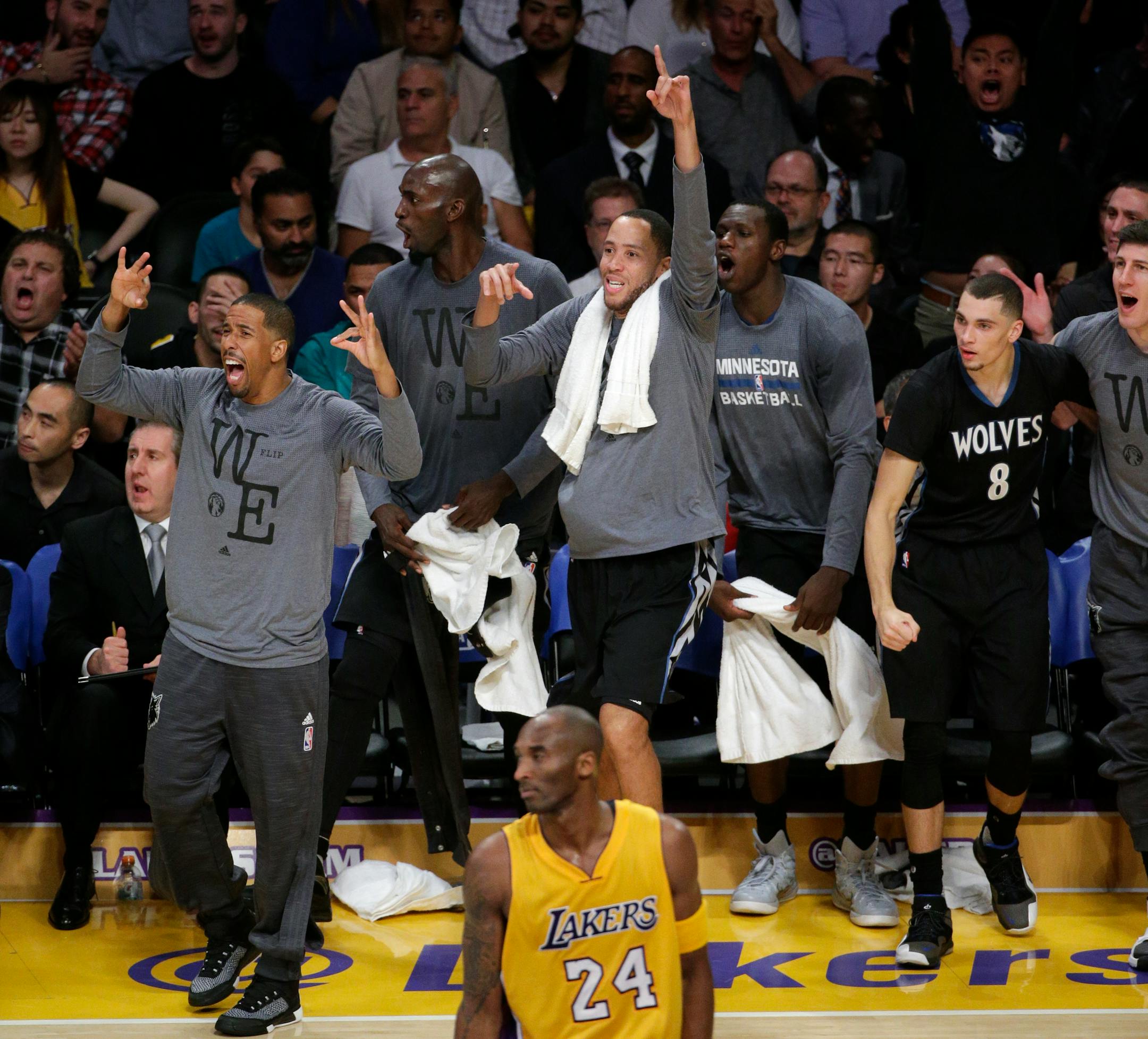 The Minnesota Timberwolves bench reacts to a three-point basket by a teammate as Los Angeles Lakers' Kobe Bryant watches during the second half of an NBA basketball game, Wednesday, Oct. 28, 2015, in Los Angeles. The Timberwolves won 112-111.