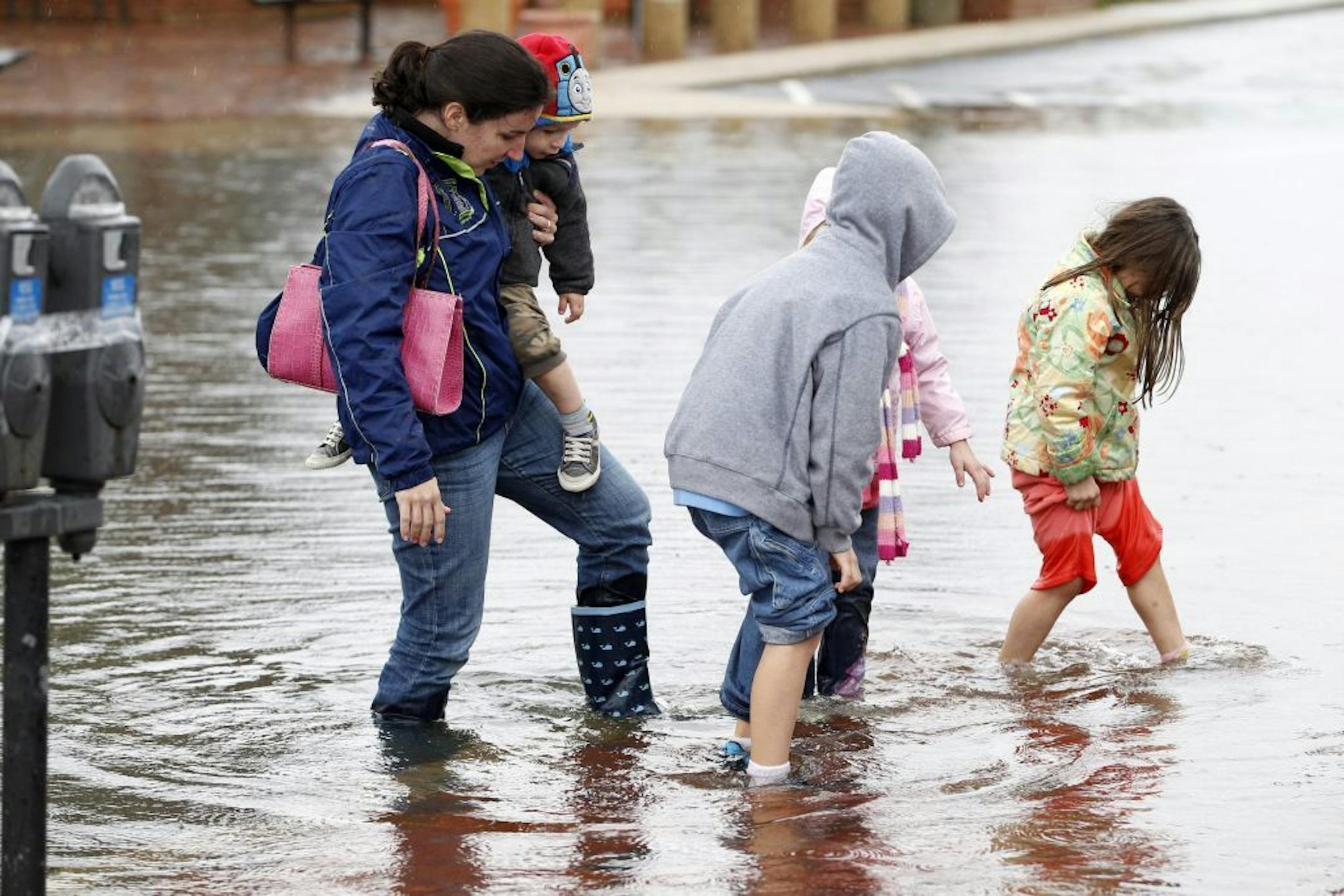 A family walks along a flooded street in downtown Annapolis, Md, Tuesday, Oct. 30, 2012, after superstorm Sandy passed over the area.