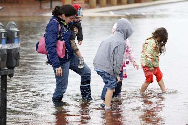A family walks along a flooded street in downtown Annapolis, Md, Tuesday, Oct. 30, 2012, after superstorm Sandy passed over the area.