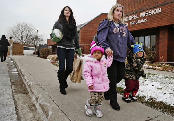 Kelli Ray of St. Paul walks with her two children Jakobe, 3, right, and Leette, 2, followed by volunteeer Randi DeMario carrying a turkey and the fixi