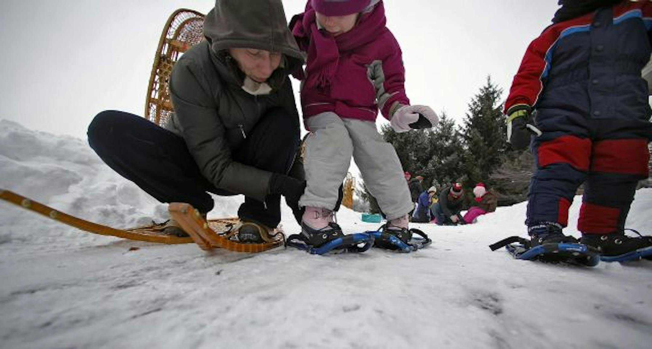 Kelly Moore helped her daughter, Marion, 5, attach a pair of small snow shoes to her boots before beginning their walk.