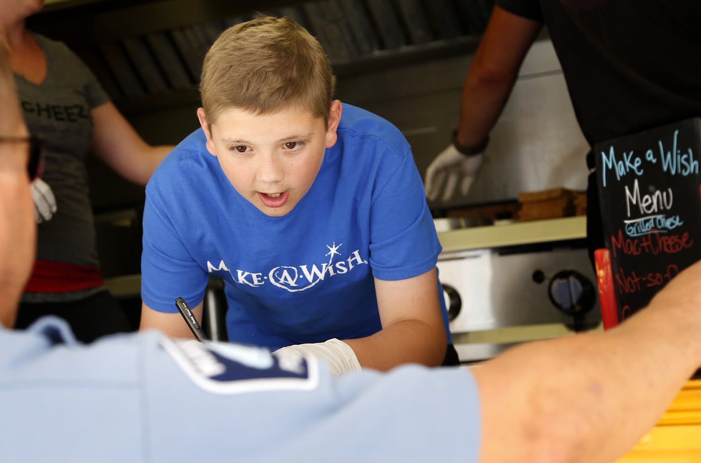 Lucas Hobbs, 12, took an order from a Minneapolis police officer while working in a food truck Monday in front of Minneapolis City Hall. Lucas, whose Hodgkin lymphoma is in remission, got his wish to feed others, thanks to the Make-A-Wish Foundation and the Minnesota Food Truck Association.