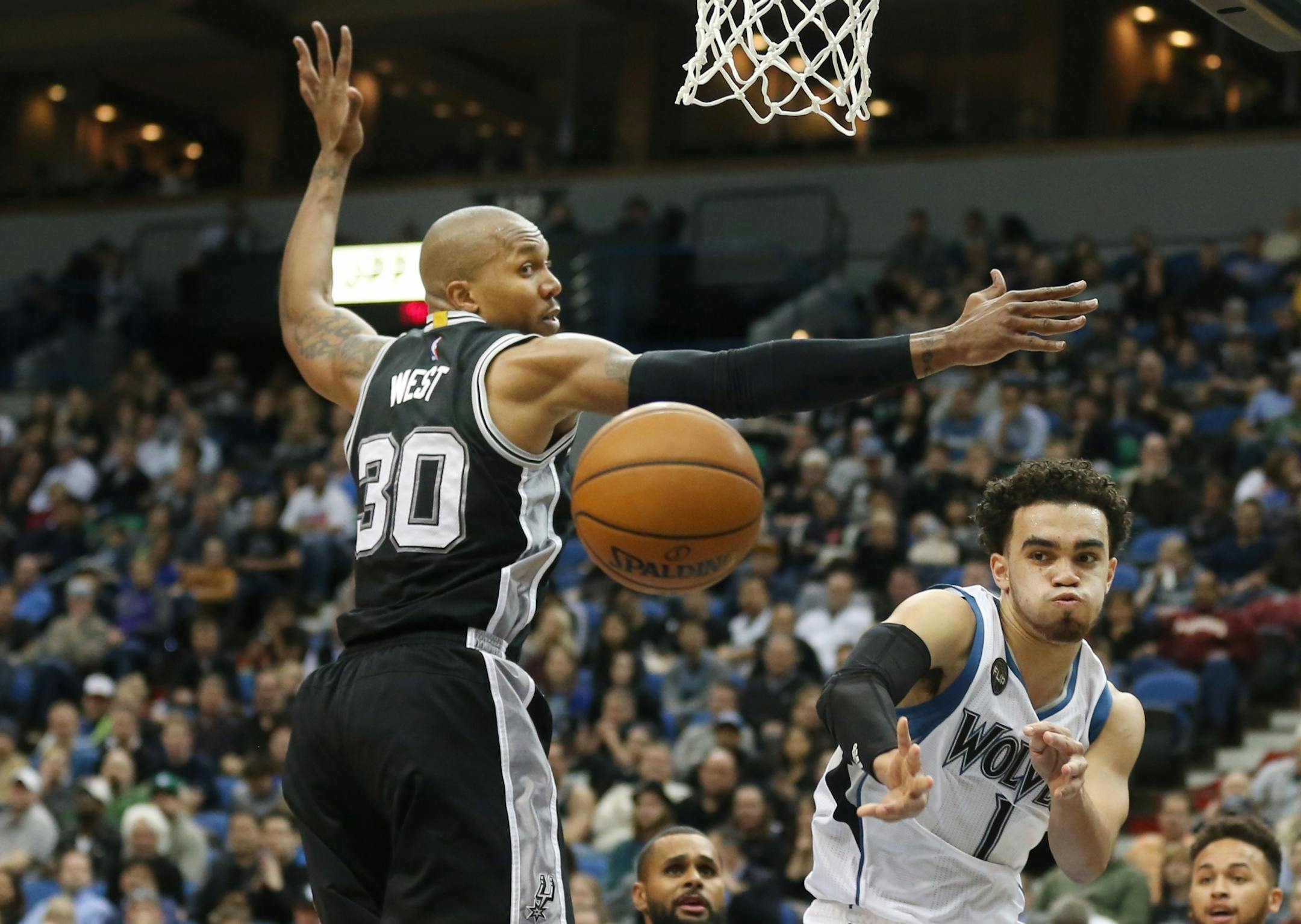 Minnesota Timberwolves guard Tyus Jones (1) made a pass around San Antonio Spurs forward David West (30) at Target Center Tuesday March 8, 2016 in Minneapolis , MN.