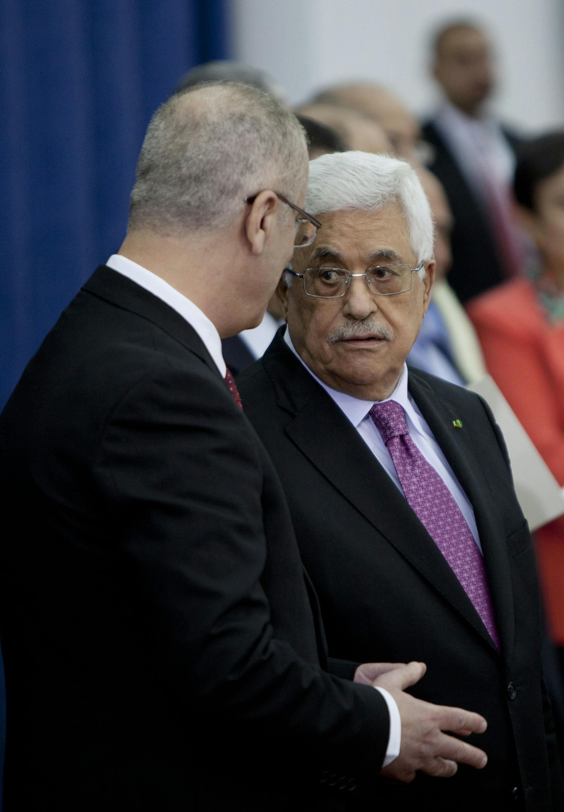 Palestinian President Mahmoud Abbas, right, talks with Palestinian Prime Minister Rami Hamdallahin during a swearing-in ceremony of its unity government in the West Bank city of Ramallah on Monday, June 2, 2014. Abbas on Monday swore in a Palestinian unity government, taking a major step toward ending a crippling territorial and political split among the Palestinians but also setting the stage for new friction with Israel. (AP Photo/Majdi Mohammed)