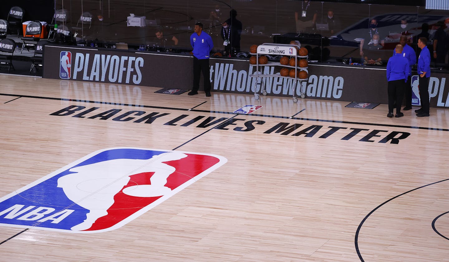 Referees stand on an empty court before the start of a scheduled game between the Milwaukee Bucks and the Orlando Magic for Game 5 of an NBA basketball first-round playoff series, Wednesday, Aug. 26, 2020, in Lake Buena Vista, Fla. (Kevin C. Cox/Pool Photo via AP)