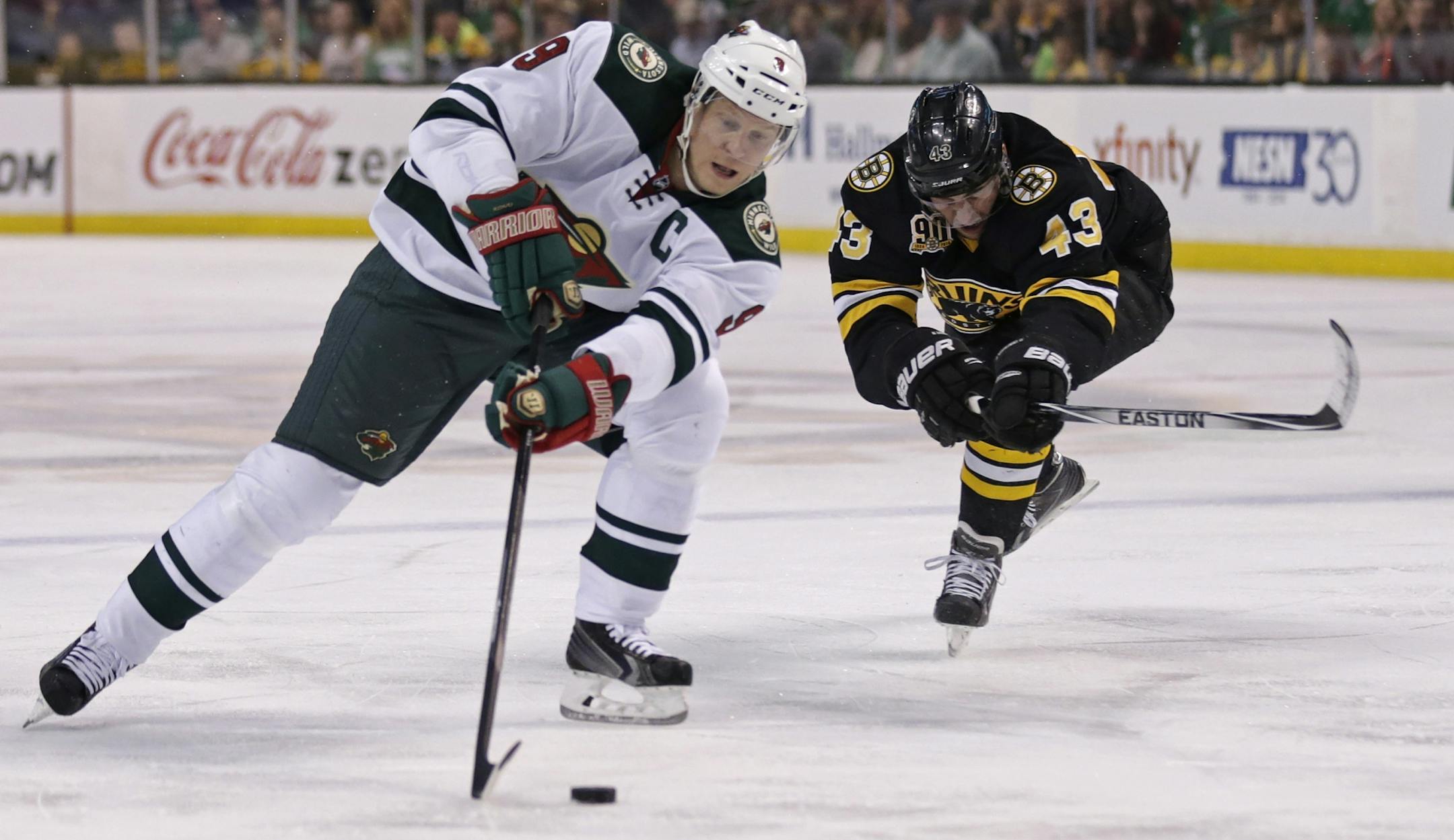 Minnesota Wild center Mikko Koivu (9) skates past Boston Bruins defenseman Matt Bartkowski (43) as he sets up a shot on goal during the first period of an NHL hockey game, Monday, March 17, 2014, in Boston.
