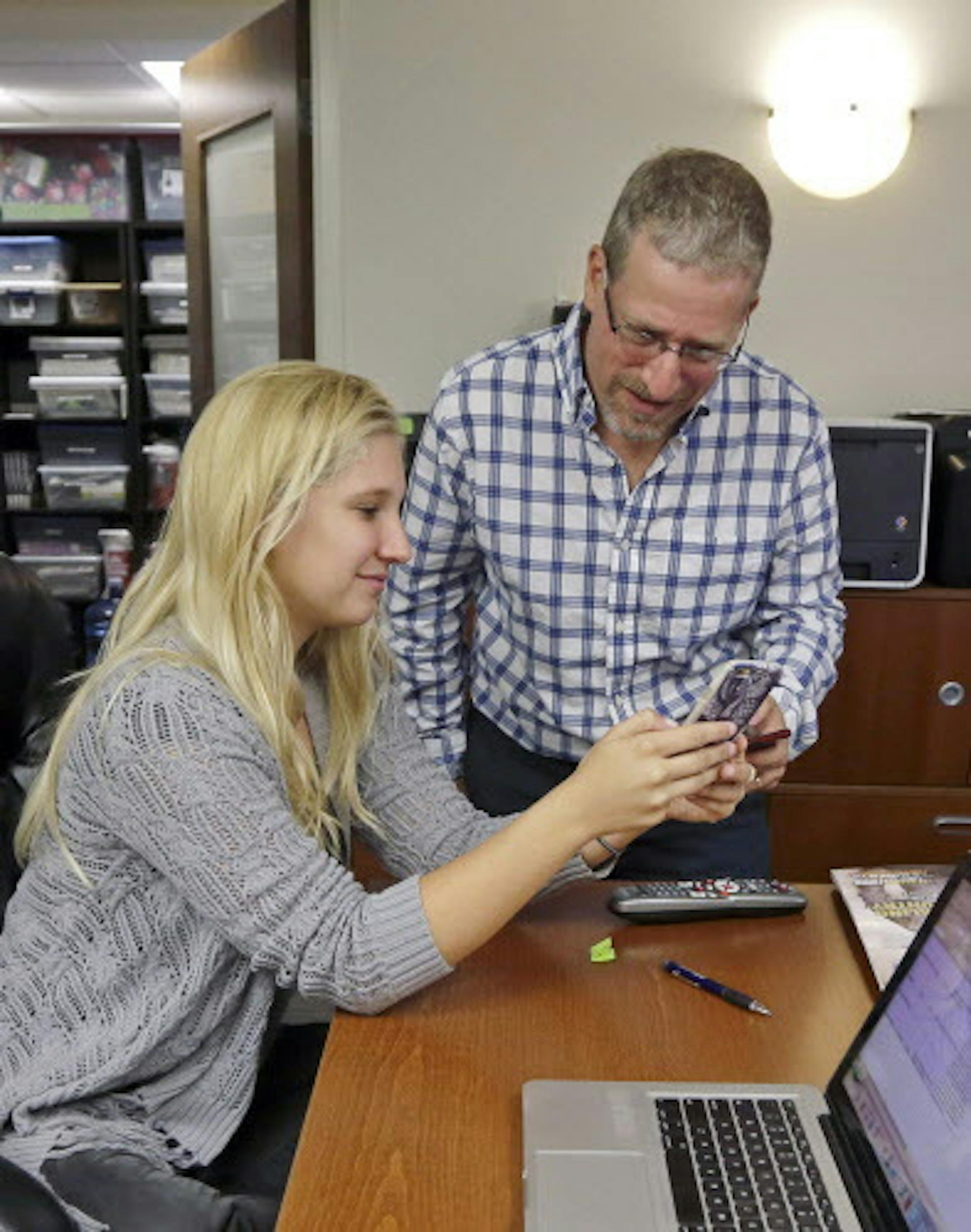 In this June 29, 2015, photo, Alexis Acosta, account coordinator, left, shows Fish Consulting director of social media Toby Srebnik a question that had been asked during a weekly forum streamed via Periscope, at the company's offices in Hollywood, Fla. Marketing successes with Facebook, Twitter, Pinterest and Instagram have encouraged companies to try streaming apps like Periscope and Meerkat. (AP Photo/Alan Diaz)