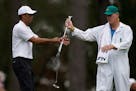 Tiger Woods exchanges his clubs with his caddie on the third hole during a practice round for the Masters on Wednesday.