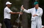Tiger Woods exchanges his clubs with his caddie on the third hole during a practice round for the Masters on Wednesday.