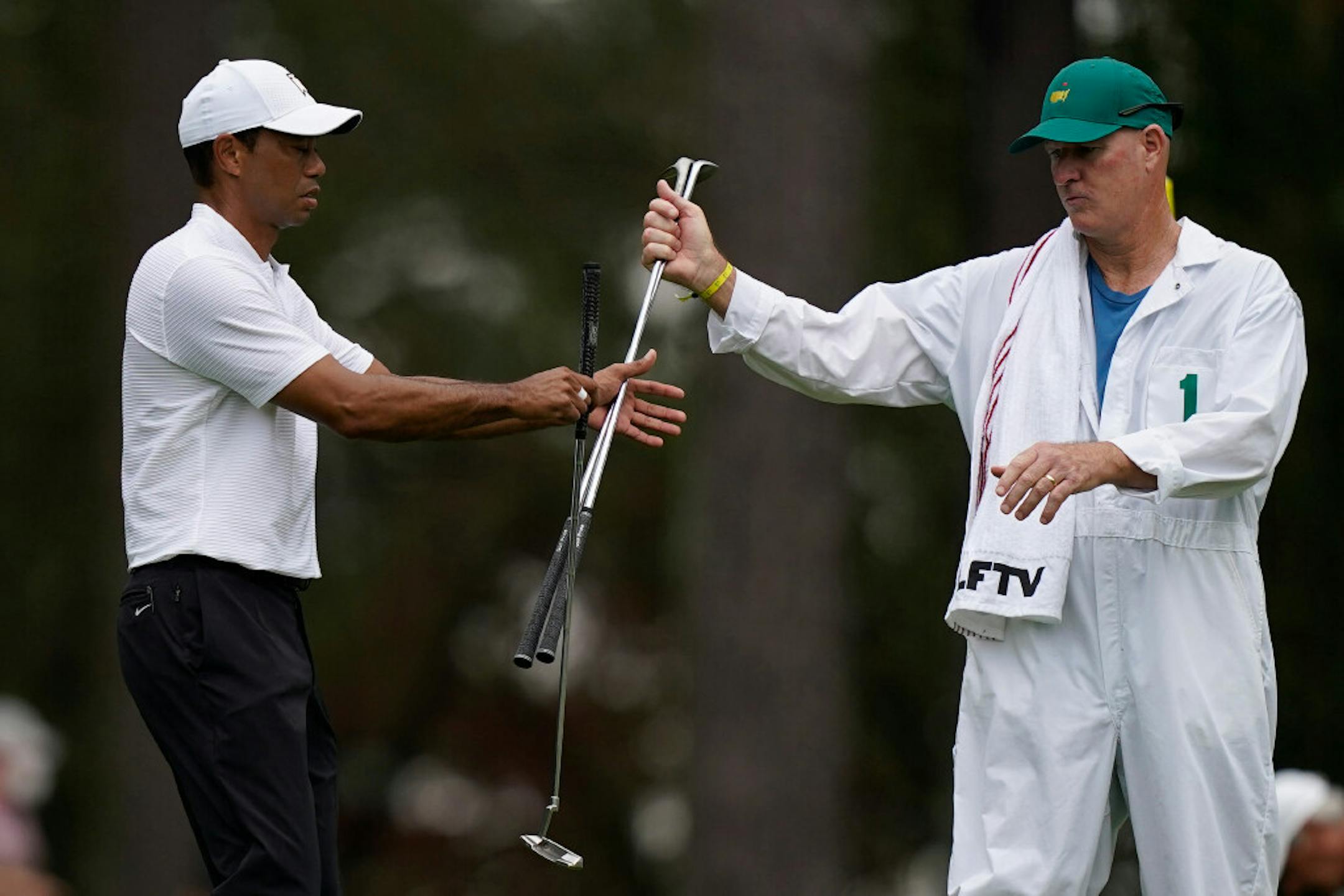 Tiger Woods exchanges his clubs with his caddie on the third hole during a practice round for the Masters on Wednesday.