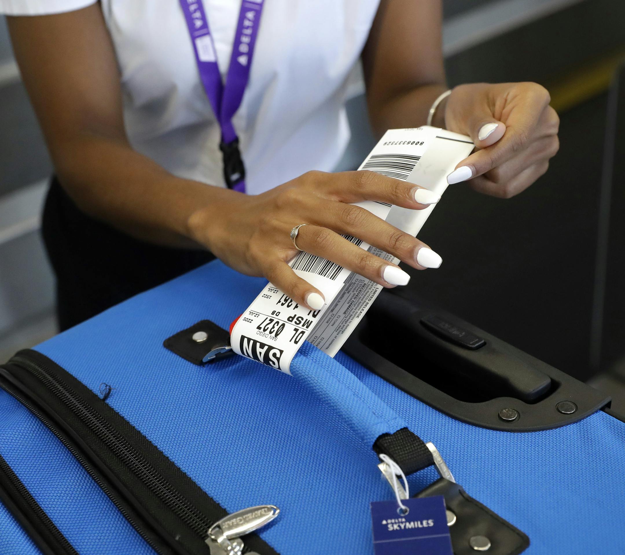 In this July 12, 2016, photo, Delta Air Lines employee Helen Evans places an RFID-enabled baggage tag on a passenger's checked bag at Baltimore-Washington International Thurgood Marshall Airport in Linthicum, Md. Delta Air Lines is rolling out new technology to better track bags throughout its system. (AP Photo/Patrick Semansky)