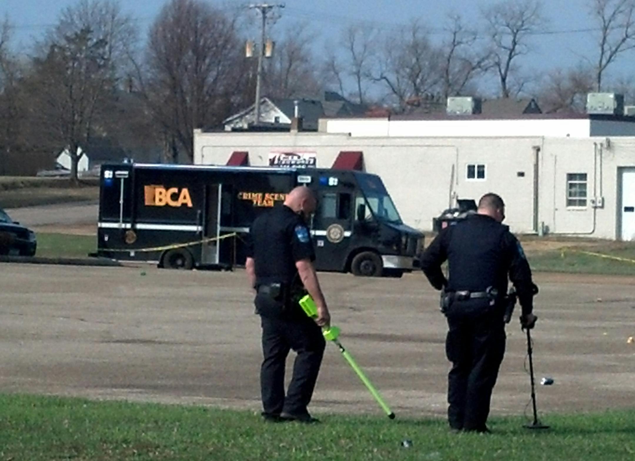 Authorities use metal detectors to search the scene of a shooting early Sunday, April 20, 2014 at a parking lot near the Kato Entertainment Center in Mankato, Minn. Four people were shot and one was killed.