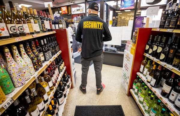 A security guard stood in an aisle at Greenway Liquors in Loring Park, where numerous looting incidents prompted the owner to put up boards on windows