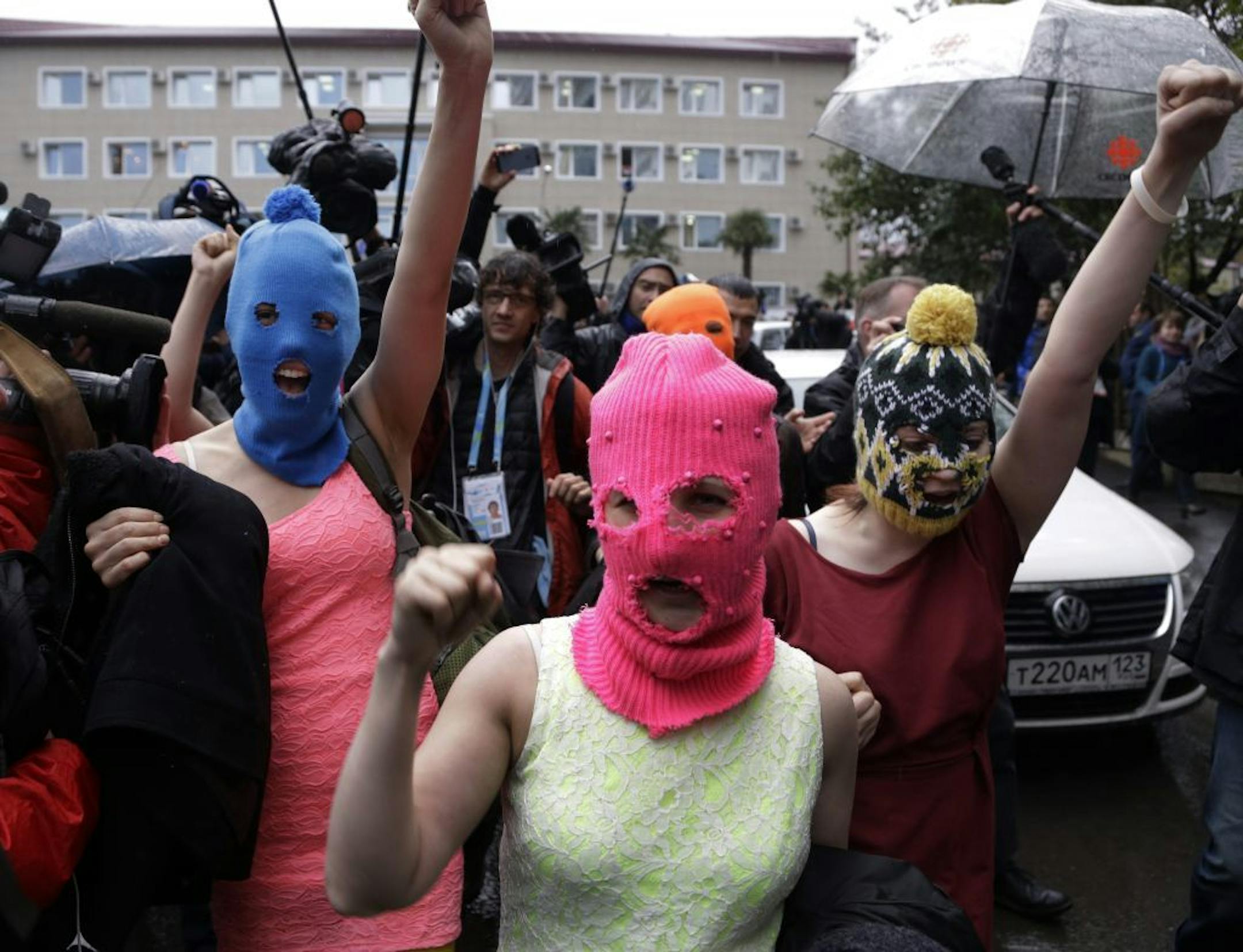 Russian punk group Pussy Riot members Nadezhda Tolokonnikova, in the blue balaclava, and Maria Alekhina, in the pink balaclava, make their way through a crowd after they were released from a police station, Tuesday, Feb. 18, 2014, in Adler, Russia. No charges were filed against Tolokonnikova and Alekhina along with the three others who were detained.