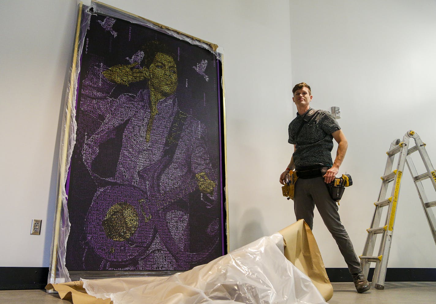 Installer Carson Giblette stands next to &#x201c;Purple Reign&#x201d; after the piece is unveiled Wednesday at U.S. Bank Stadium.