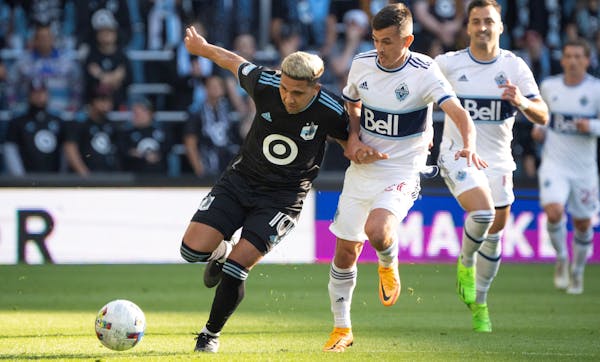 Minnesota United midfielder Emanuel Reynoso (10) pursued the ball as he was held by Vancouver Whitecaps midfielder Andrés Cubas (20) in the first hal