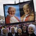 Nuns hold up a poster with portraits of Pope John Paul II, left, and John XXIII, in St. Peter's Square at the Vatican Sunday, April 27, 2014. Pope Fra