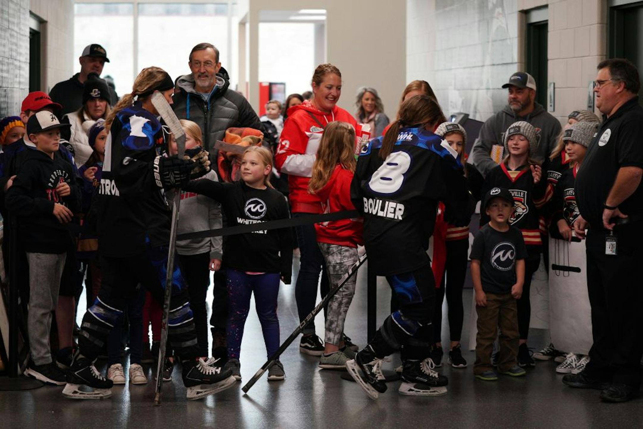 Whitecaps forward Allie Thunstrom (9) and defenseman Amanda Boulier (8) greeted young fans as they made their way from the ice to the locker room after their pregame warmup.