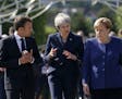 German Chancellor Angela Merkel, right, speaks with French President Emmanuel Macron, left, and British Prime Minister Theresa May after meeting at a 