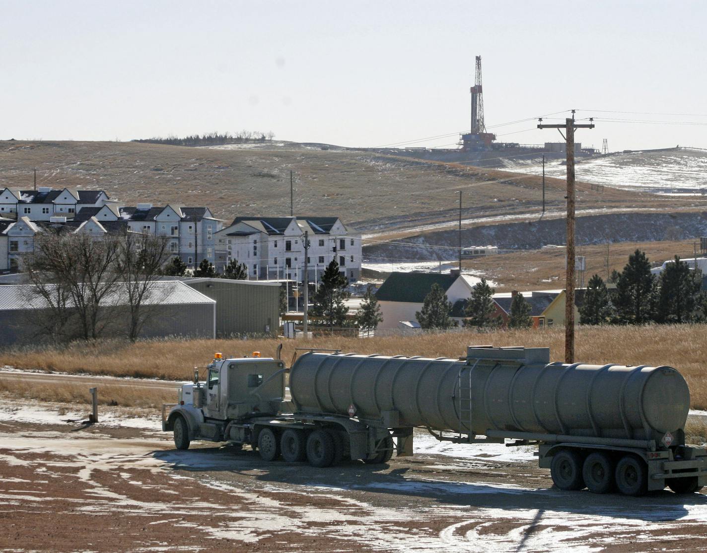 FILE - In this Feb. 26, 2014 file photo, an oil truck sits in a dirt lot near a new housing development in Watford City, N.D. The housing development is part of the towns growth explosion from the Bakken oil boom. The White House, in a report released Wednesday, July 9, 2014, singled out the oil patch of northwestern North Dakota and northeastern Montana as part of its 2014 national drug control strategy. The report says dramatic increases in crime in the region has overwhelmed state, local and